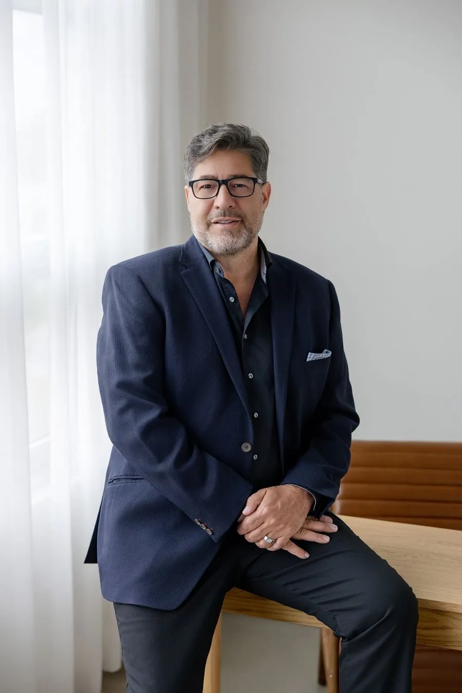 Gino DeMichele seated on the edge of a desk
